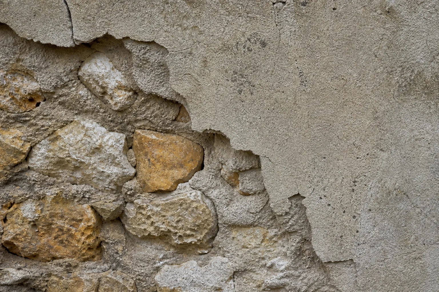 Enduit ciment fissuré sur un mur en pierre meulière dans le Val-d'Oise (95)